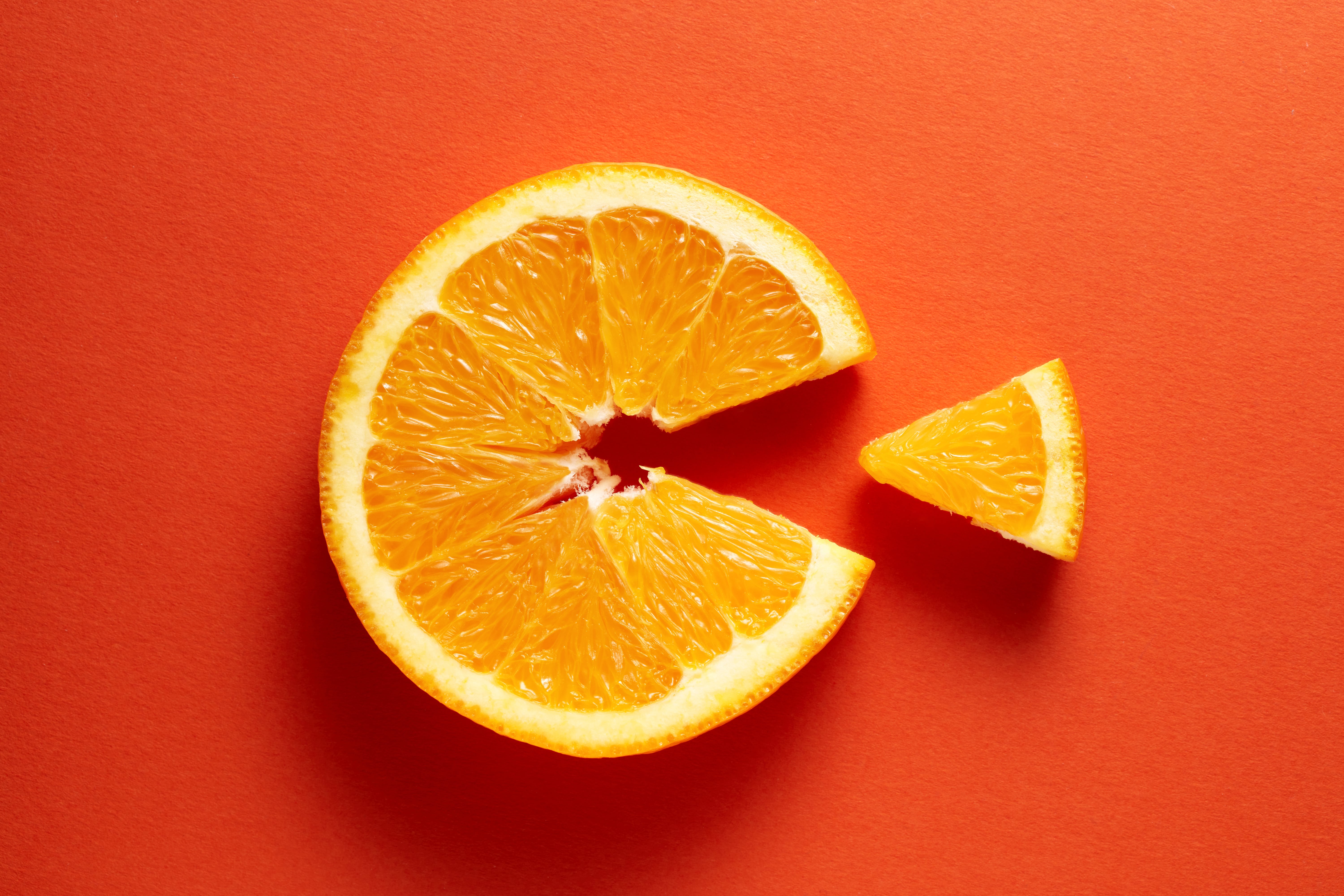 A slice of vitamin C-packed orange set against a bright orange back ground