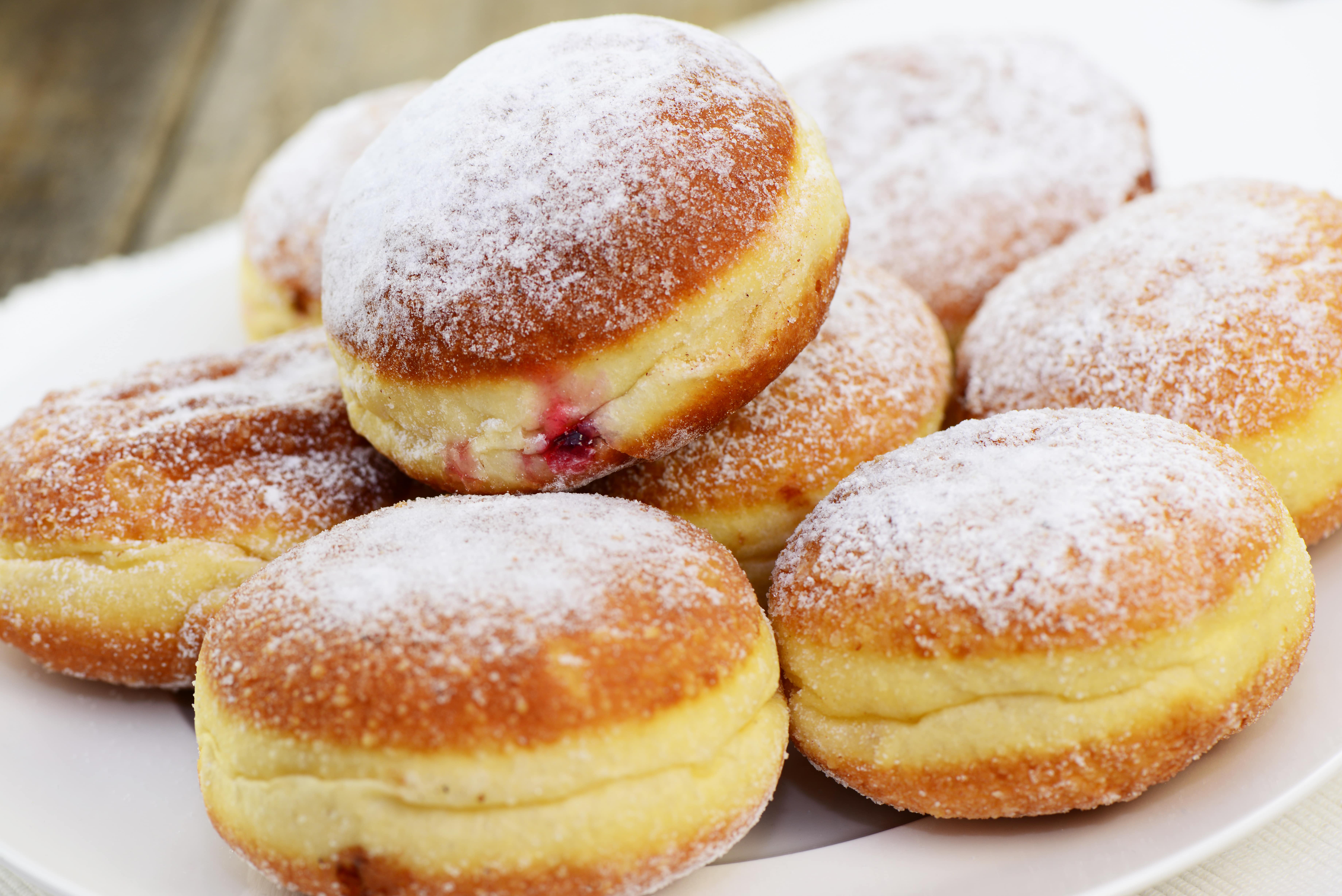 Plate of jam doughnuts dusted with icing sugar.