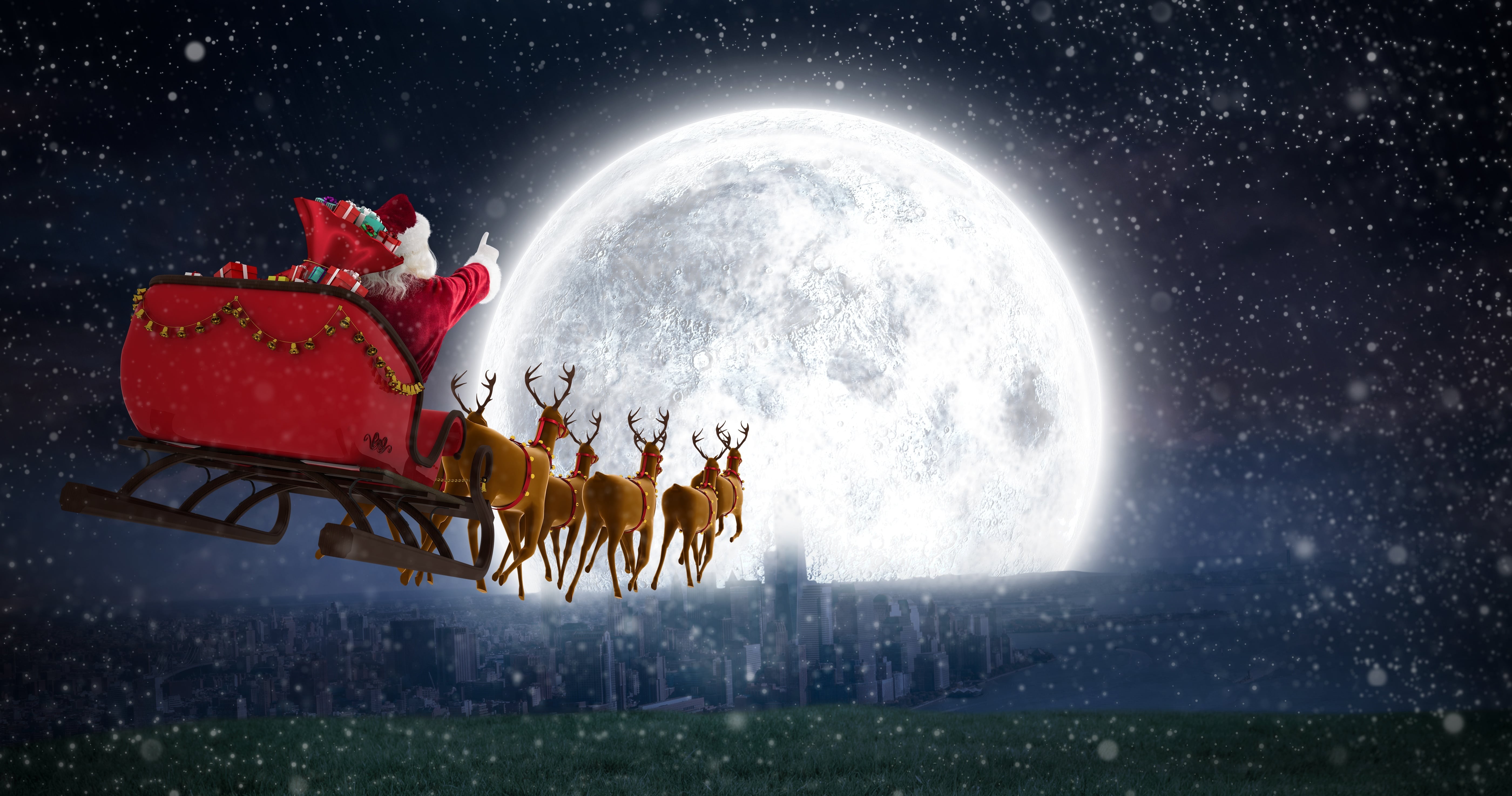Santa is flying towards the moon at night in his reindeer-drawn sleigh. He is pointing ahead.