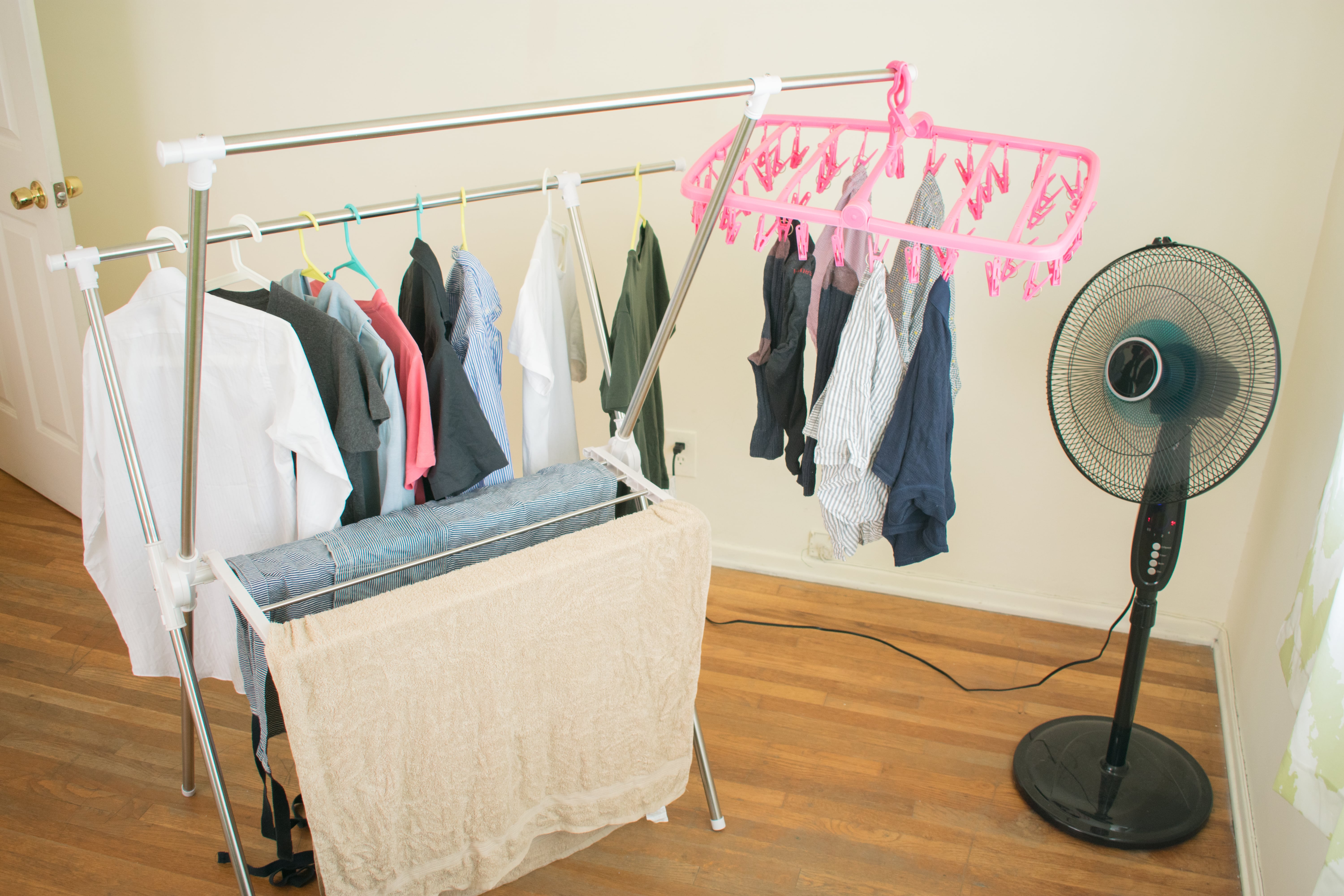 A floor-standing fan positioned next to an indoor clothes airer to circulate the air and encourage the washing to dry faster