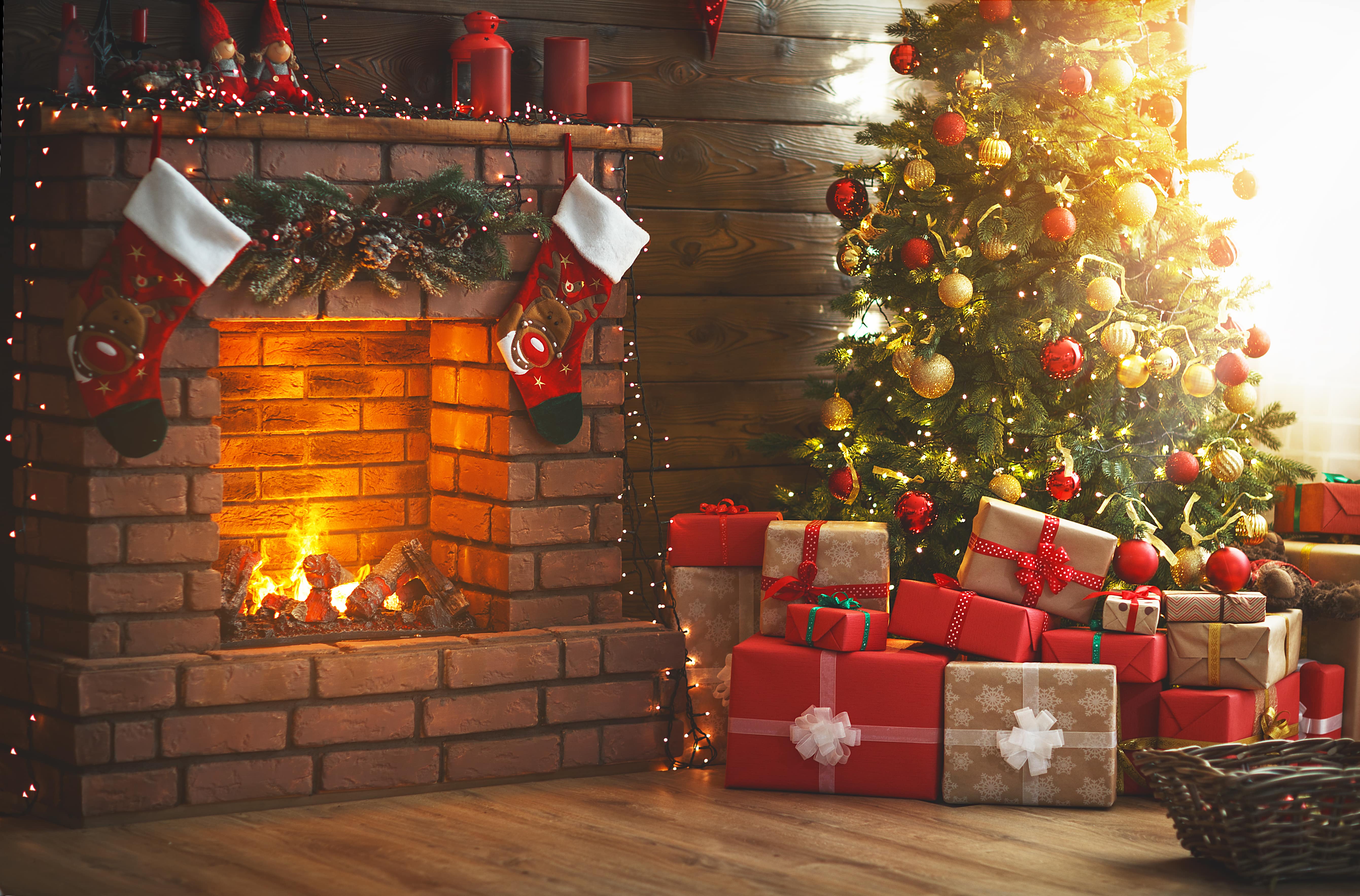 A home at Christmas time. The presents are nestled under the Christmas tree, the stockings are hung on the fireplace and twinkling Christmas lights festively light the room.