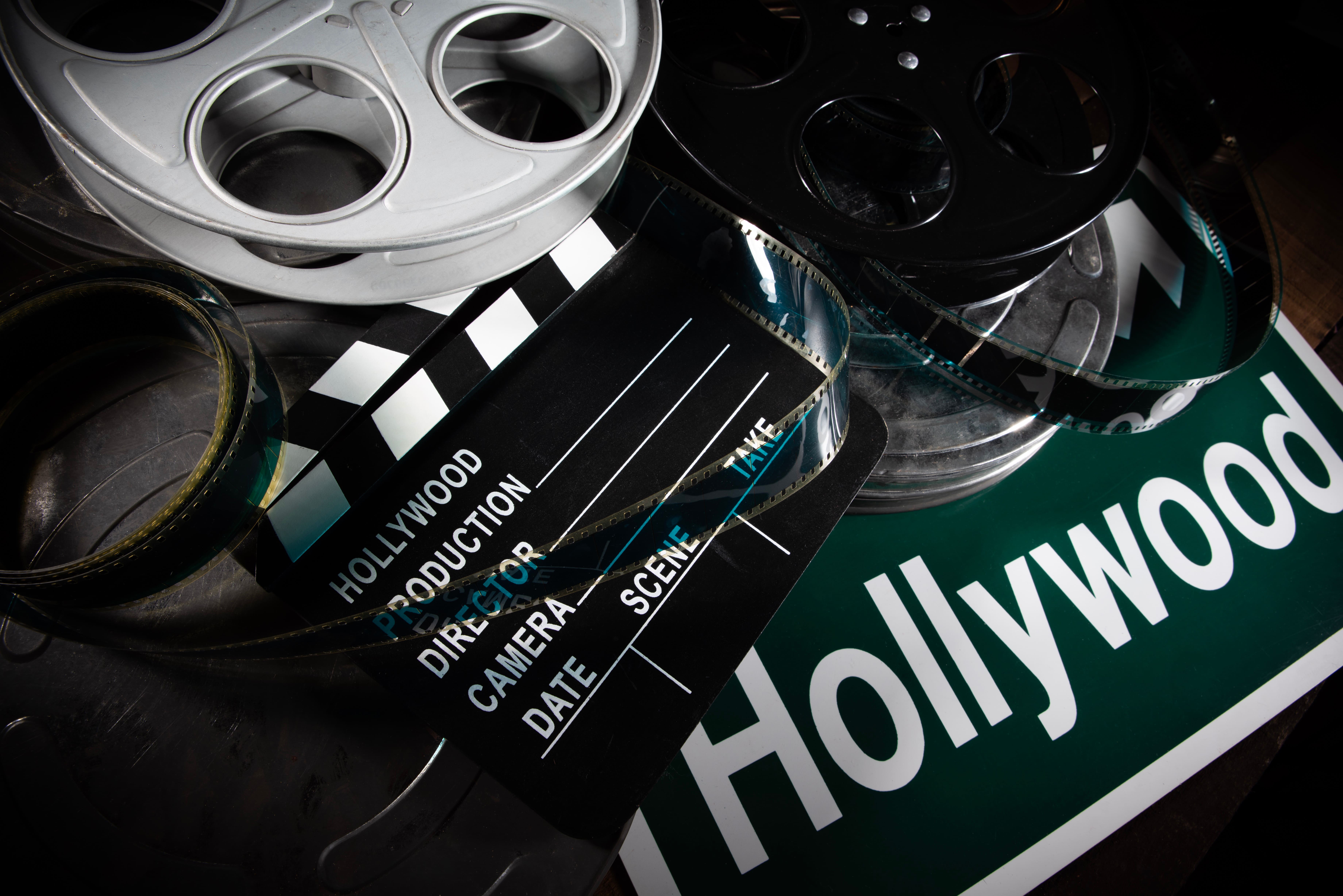 A collection of film reels and cases, a clapper board, and a Hollywood road sign.