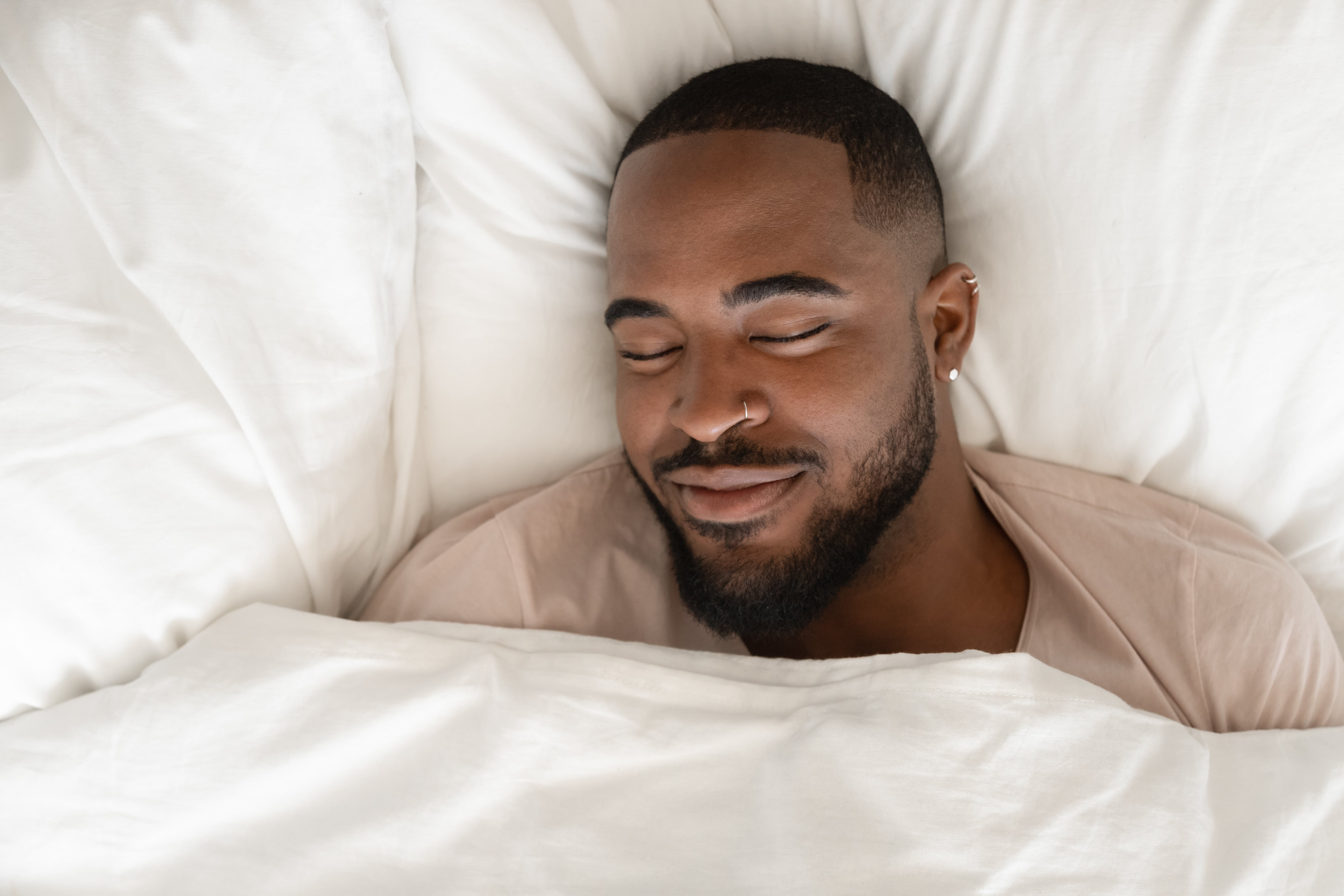 Bird's eye view of a man on a bed smiling in his sleep 