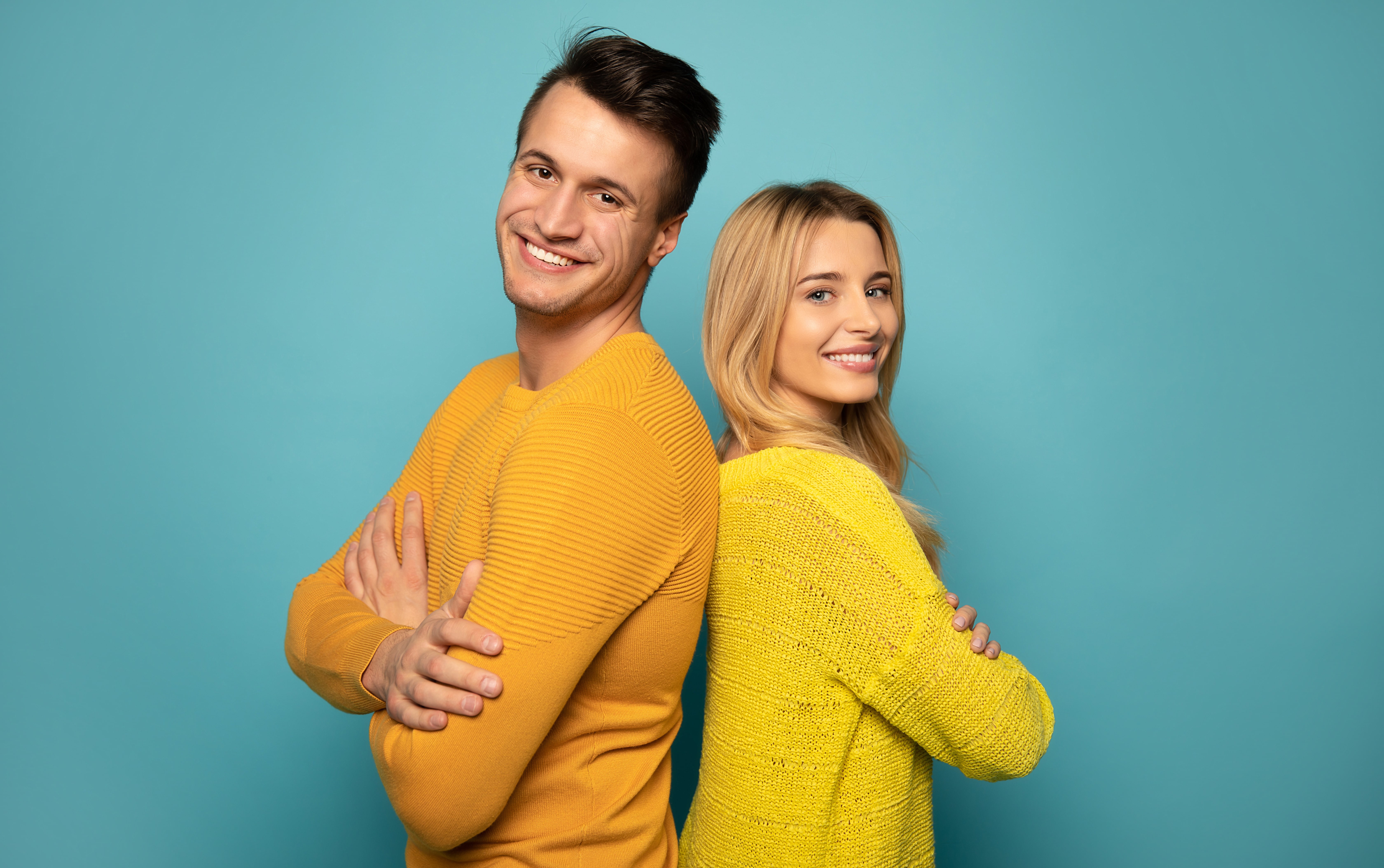 Man and Woman Standing Back to Back Facing Front and Smiling