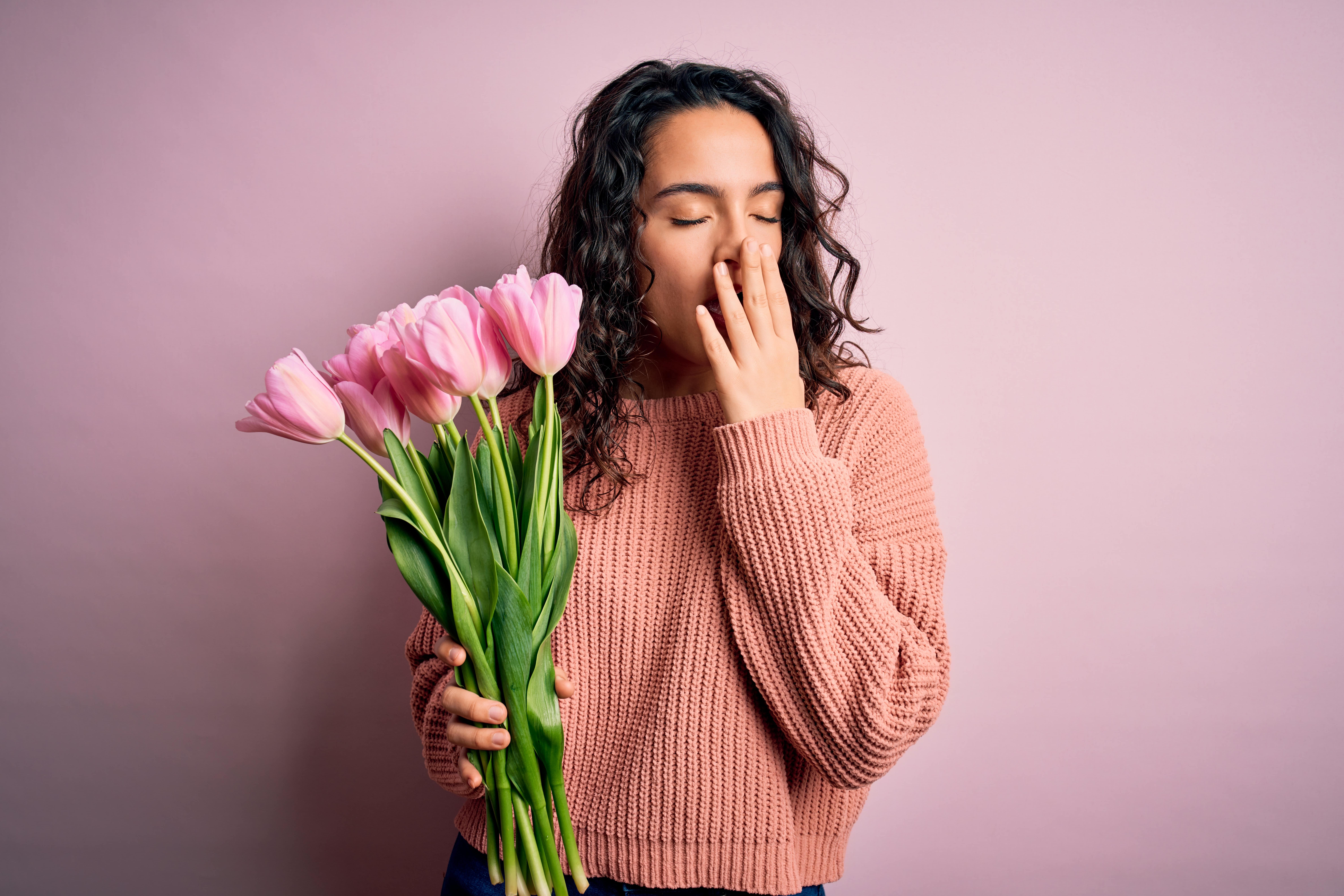 Woman holding pink flowers and yawning