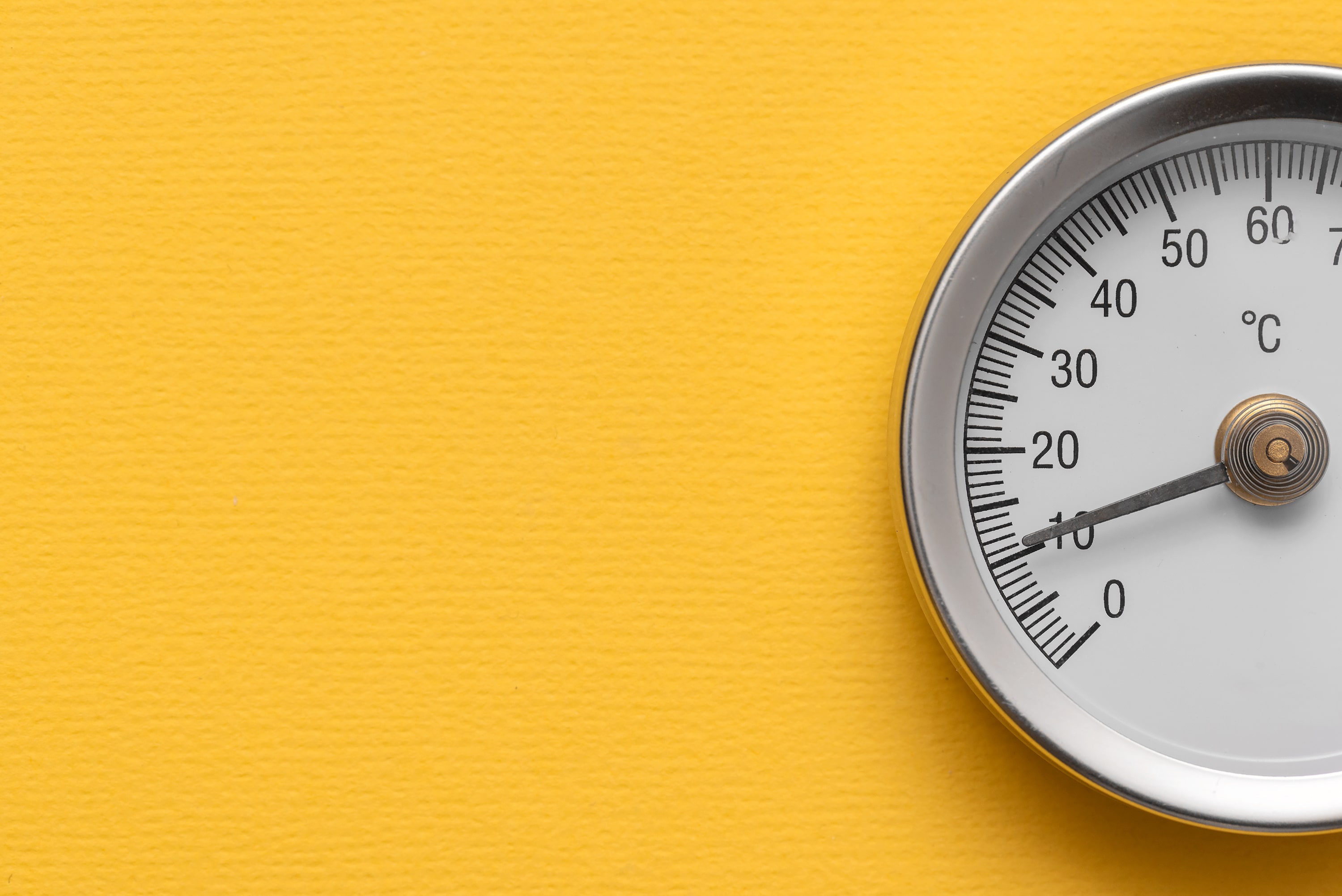 Circular temperature meter on a yellow background