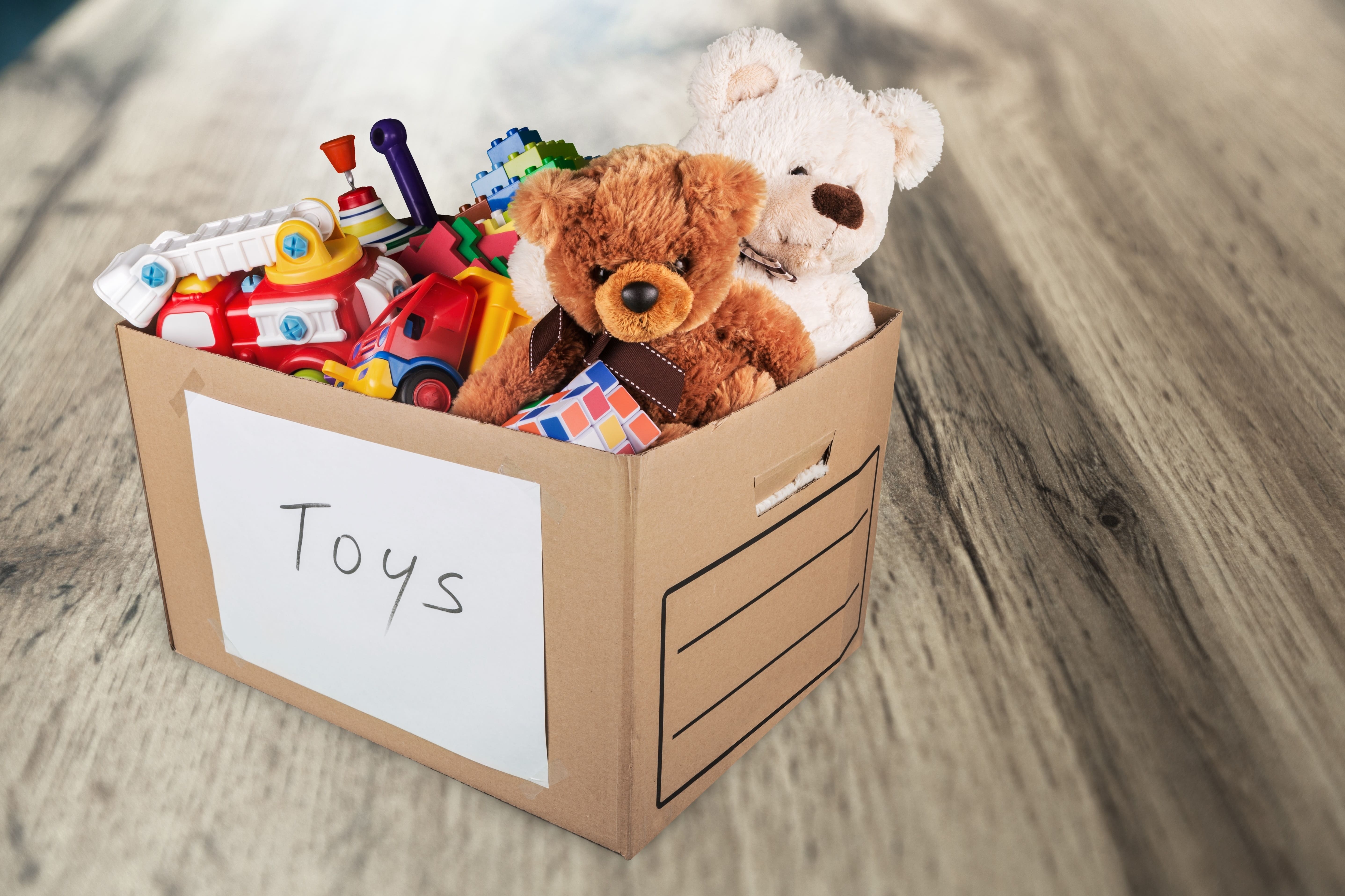 cardboard box labelled toys filled with toys and teddies sits on a wooden desk