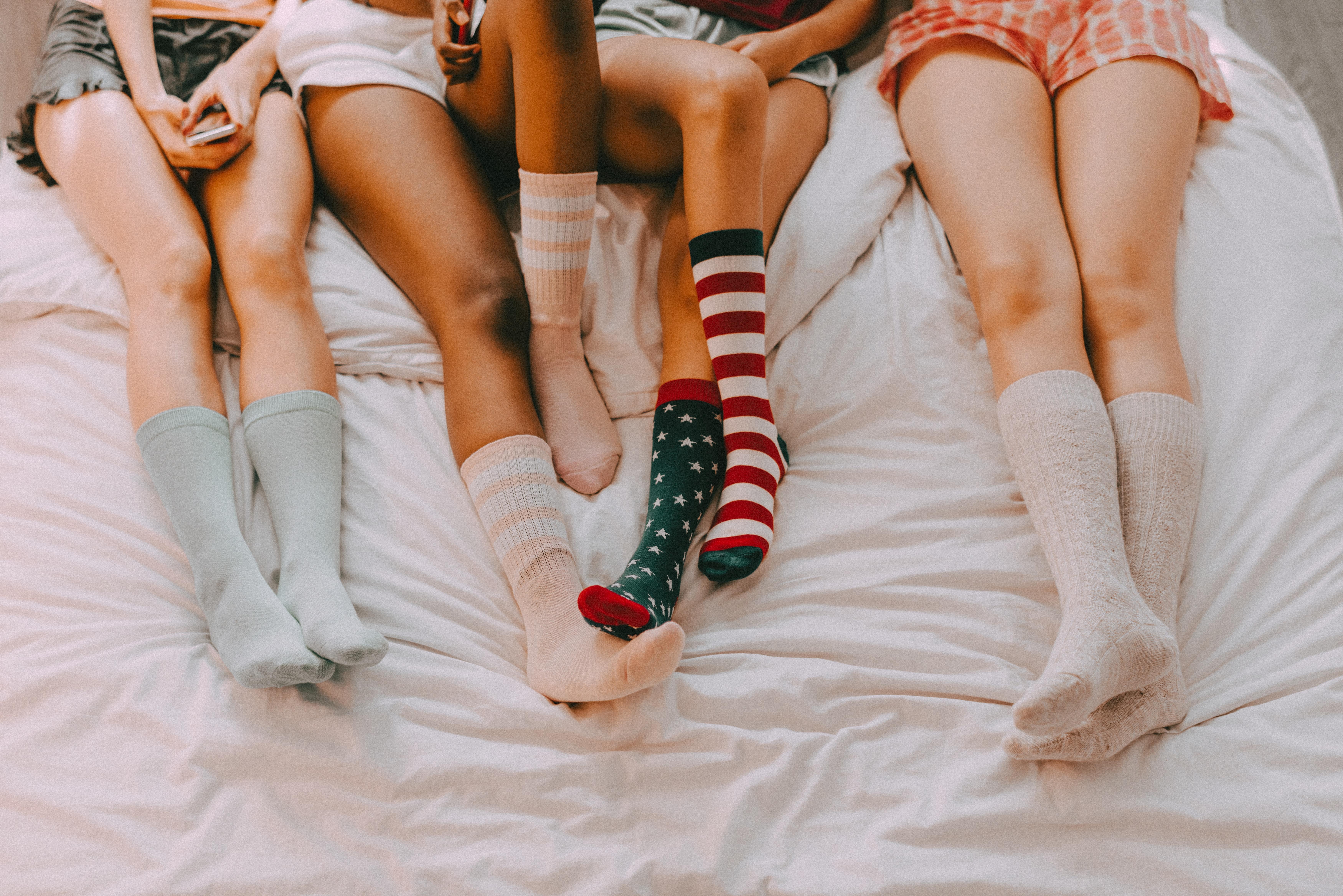 four pairs of girls legs each wearing mid calf length socks in various patterns and colours and pyjama shorts.