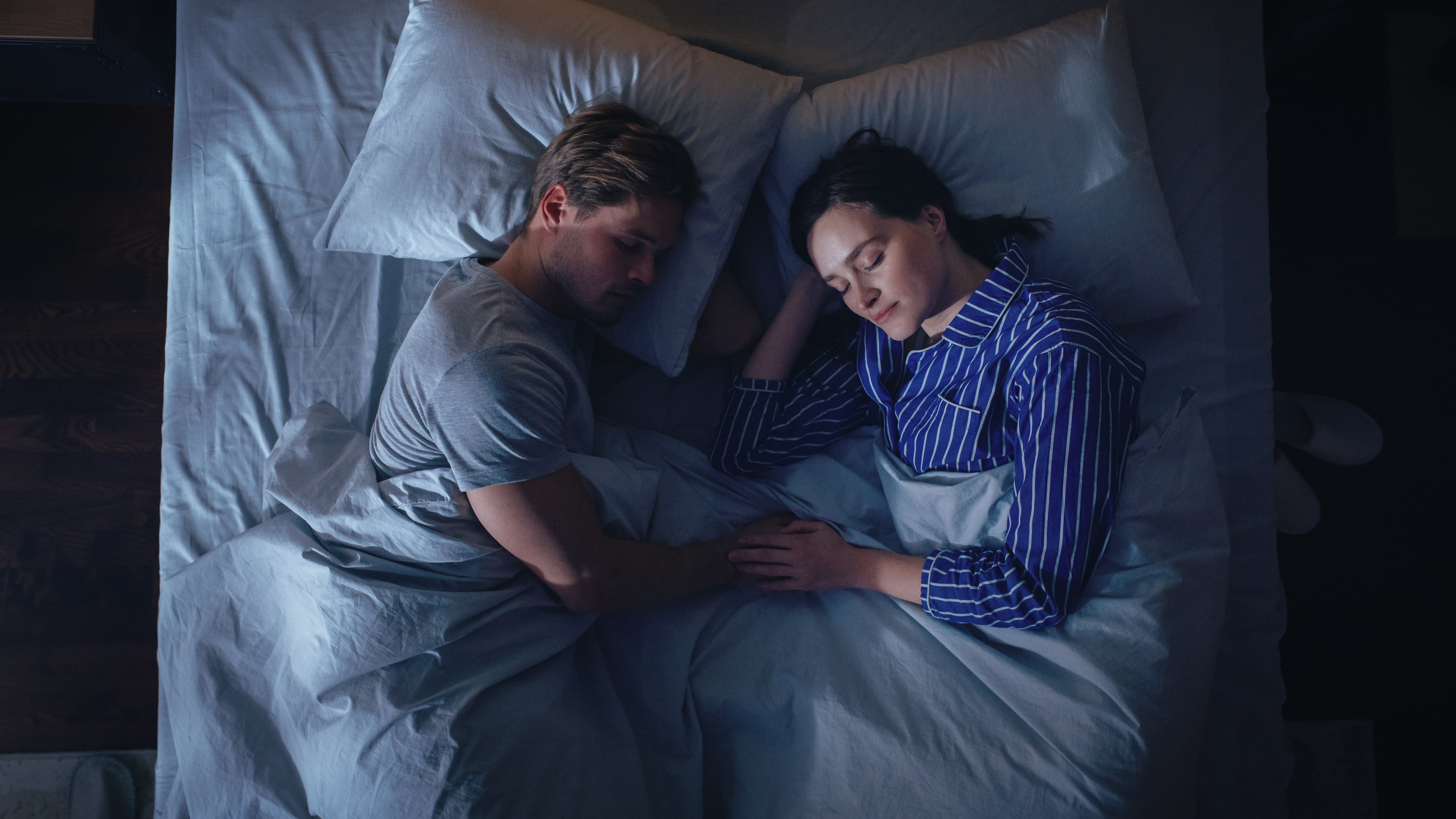 A couple sleeping in bed facing each other