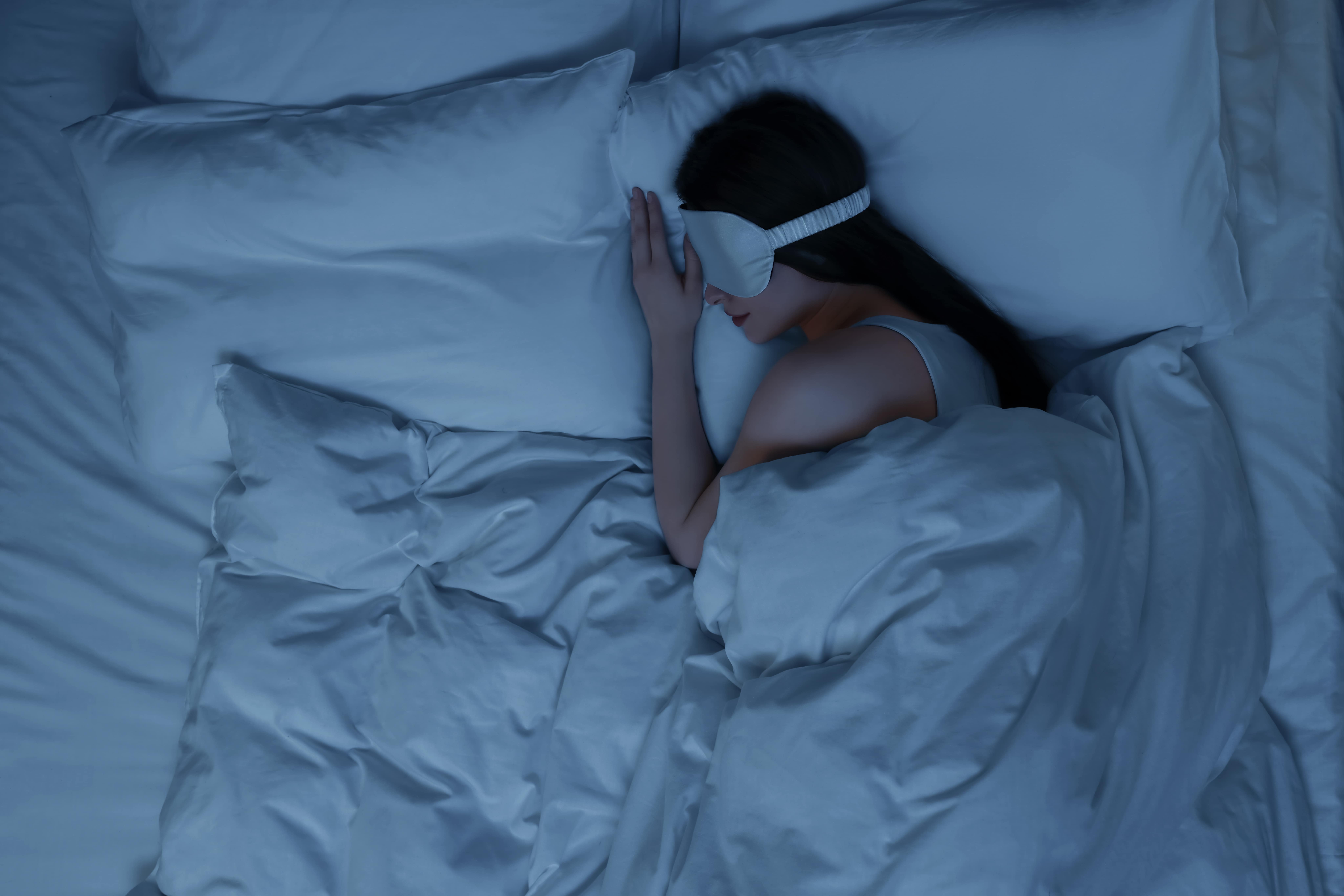 A lady asleep in the dark wearing an eye mask to prevent light disturbances affecting her sleep quality