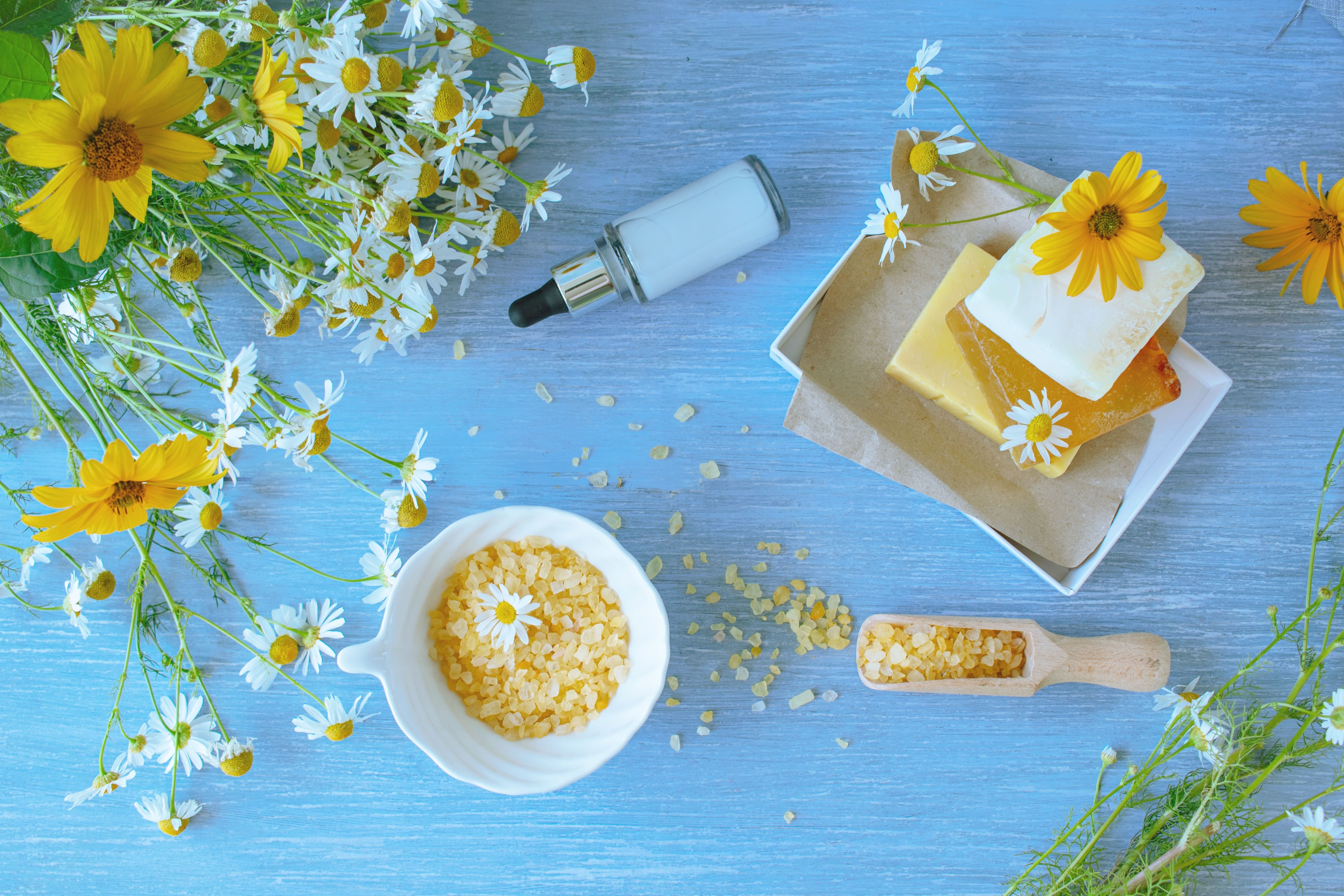 A display of chamomile flowers, soaps and crystals set against a backdrop of blue-washed wood