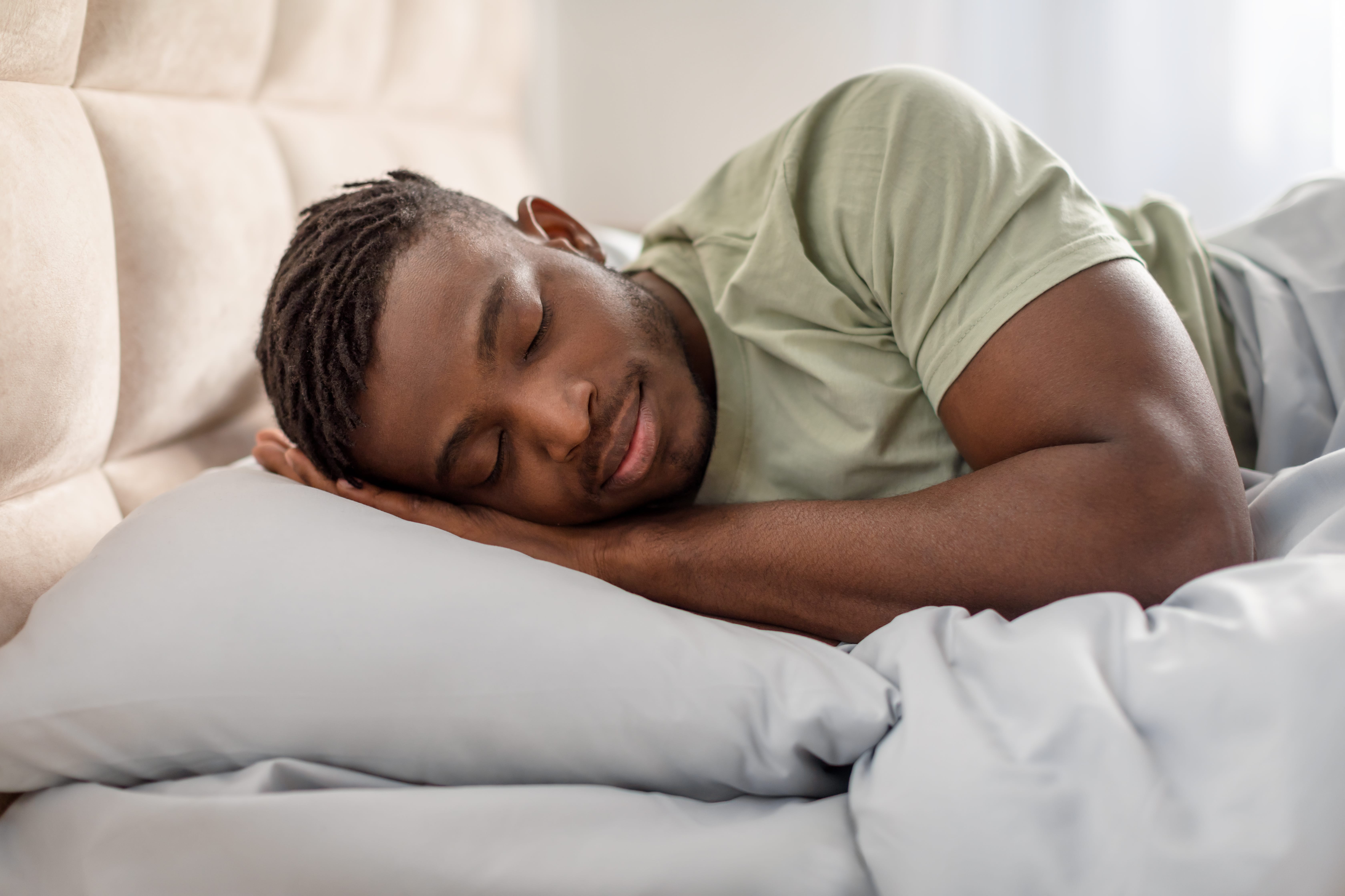 A man sleeping soundly on his side, alone in bed, with plenty of space to move around and no worry of disturbing a bed partner.