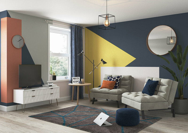 A pale grey coloured sofa bed split into two chairs and juxtaposed against abstract yellow, orange, white and navy walls with accessories featuring the same colours