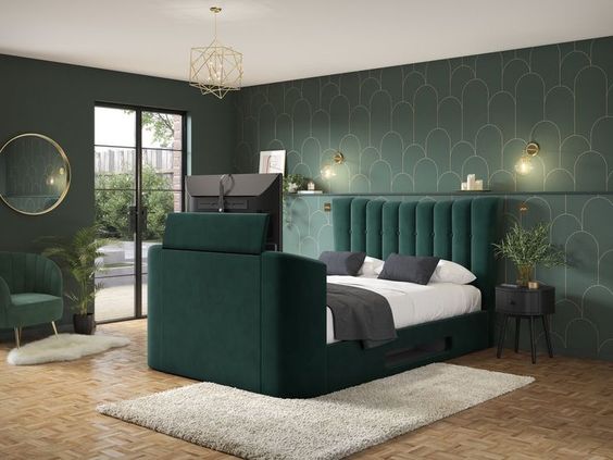 Glam pinterest board bedroom idea with green and gold feature wall paper, and emerald green upholstered bed with a hotel height headboard and lots of gold accents throughout the bedroom.