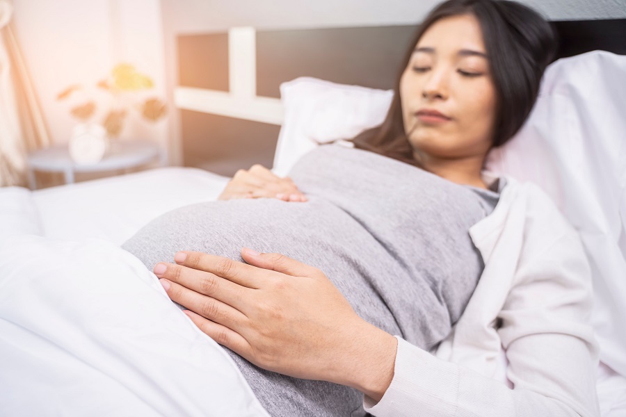 Pregnant woman relaxing in bed rubbing her tummy
