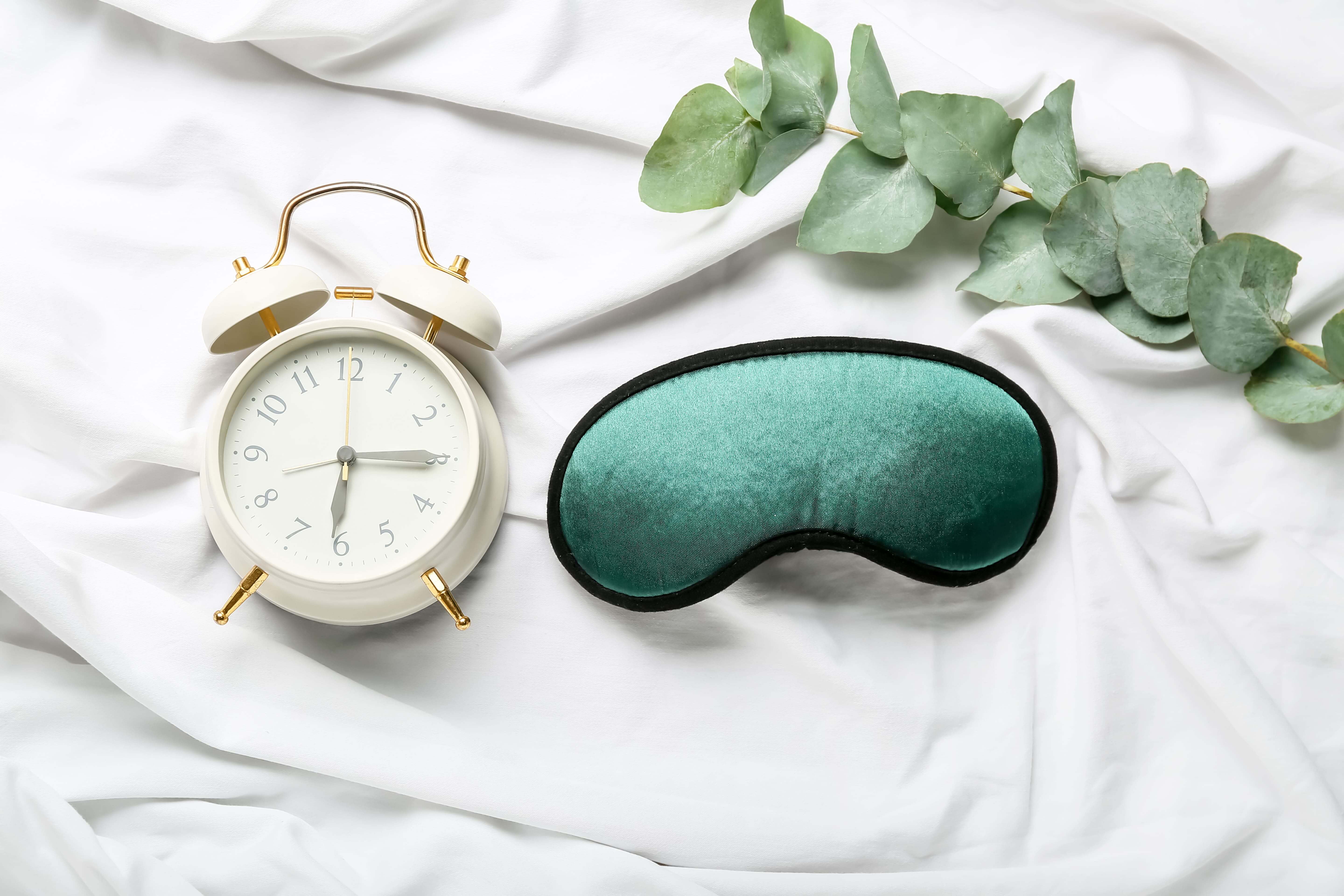 Alarm and Eye mask on Bed Sheets